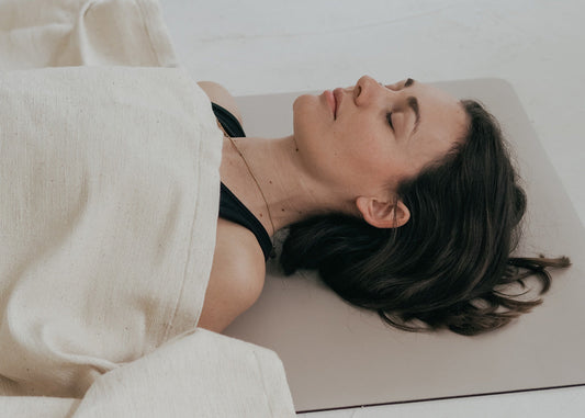 Meditieren im Liegen - Frau liegt auf einer Yogamatte