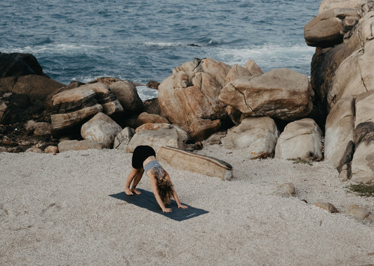 Yoga auf Reisen: Frau praktiziert am Strand Yoga 