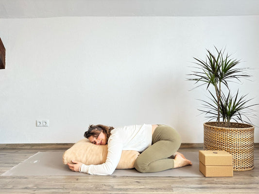Frau in einer Yin-Yoga Haltung: Unterstütztes Kind, der Oberkörper liegt auf einem Polster