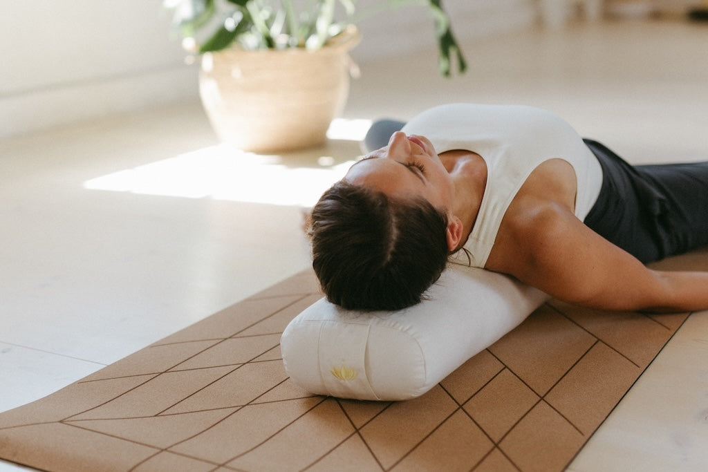Frau liegt auf Yoga-Bolster im liegenden Schmetterling